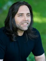 Keith Raniere has a smiling boyish demeanor in this photograph. It is hard to imagine that such a winsome person would consider branding women to be a viable option for spreading his brand of joy.
