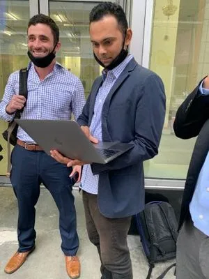 Marc Elliot and Suneel Chakravorty outside of Moira Penza's office building, with a camera crew.