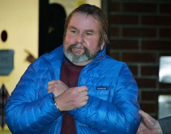 John Tighe in handcuffs, arrested for possession of child porn found on computers he did not own.