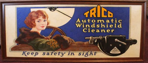 Vintage ad for Trico Automatic Windshield Cleaner featuring a woman in a car and the slogan 'Keep safety in sight'.