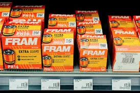 Row of FRAM oil filter boxes with orange packaging labeled EXTRA GUARD on a store shelf.