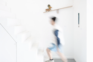 A blurred image of a man walking up an all white staircase