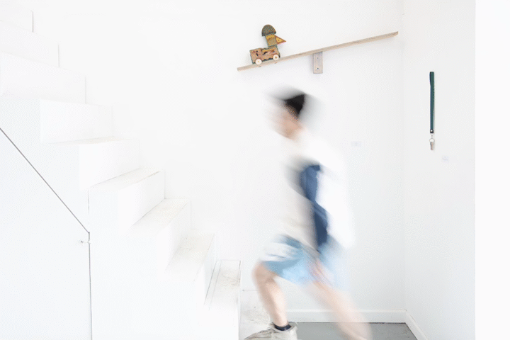 A blurred image of a man walking up an all white staircase